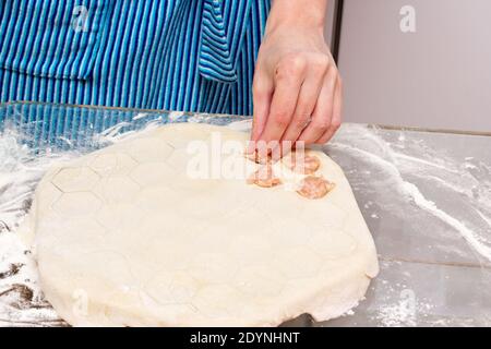 Il processo di fare i gnocchi a casa. La donna mette il ripieno di carne nell'impasto. Foto Stock