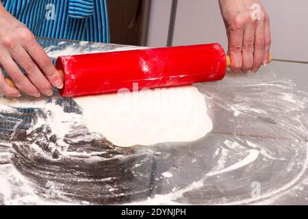 Il processo di fare i gnocchi a casa. Una donna rotola fuori l'impasto per i gnocchi. Foto Stock