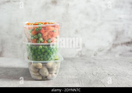 Contenitori e sacchetti di plastica con diverse verdure surgelate. Verdure conservate. Mangiare sano. Foto Stock