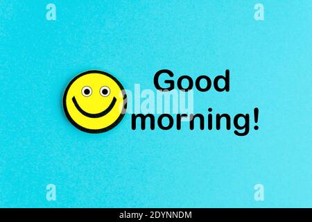 Buongiorno. Emoticon giallo su sfondo blu brillante. Auguri di buon giorno. Sorridi e positivo Foto Stock