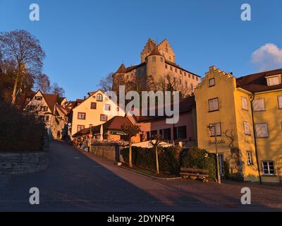 Bella vista del centro storico con vuota strada acciottolata, vecchi edifici e il simbolo castello di Meersburg sul pendio in luce notturna in inverno. Foto Stock