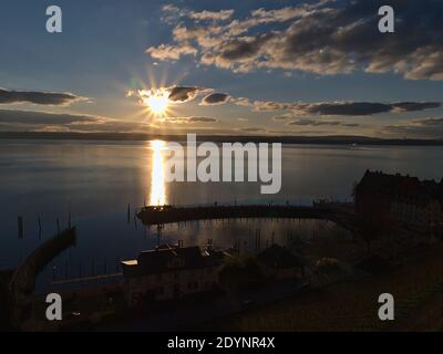 Bella vista del bacino del porto e molo in silhouette della città di Meersburg, Germania sulla riva del lago di Costanza in retroilluminata con luminoso sole serale. Foto Stock