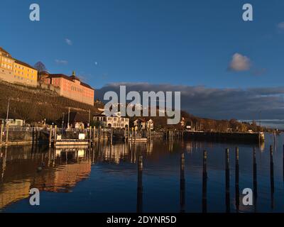 Bella vista del bacino portuale della città di Meersburg, Germania sulla riva del lago di Costanza nella luce serale nella stagione invernale con edifici storici. Foto Stock