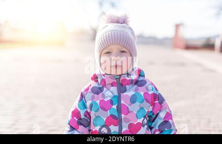 Un bambino in abiti caldi sulla strada. Ritratto di bambino di ragazza Foto Stock