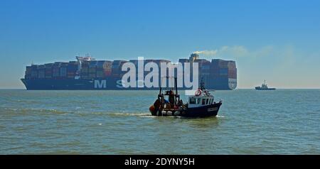 Grande nave del contenitore che lascia l'estuario di Orwell piccola barca da pesca che entra l'estuario a Felixstowe. Foto Stock