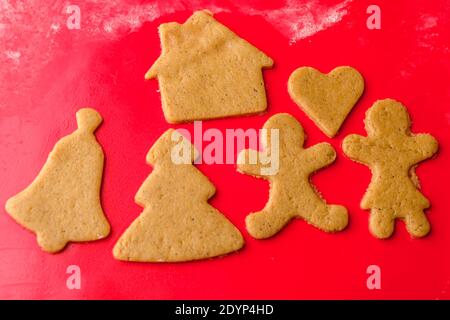 Preparare i biscotti di San Valentino come regalo. Pan di zenzero in una forma di uomo, donna, casa, albero sulla stuoia rossa di silicone. Foto Stock