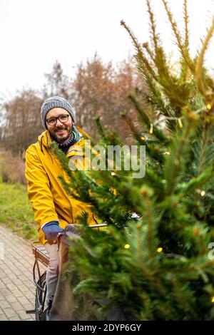 Uomo che trasporta l'albero di Natale in bicicletta Foto Stock