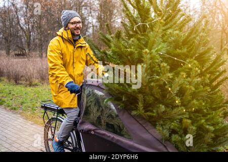 Uomo che trasporta l'albero di Natale in bicicletta Foto Stock