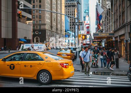 Una traversata a Manhatten, New York City, USA. Una strada trafficata a New York in una serata estiva. Tassicab e numerosi pedoni sono visti in primo piano. Foto Stock