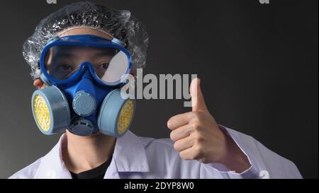 Donna asiatica dottore in una maschera medica chimica protettiva e occhiali di protezione. Indumenti uniformi da medico e filtro antiparticolato sostituibile con semimaschera Foto Stock