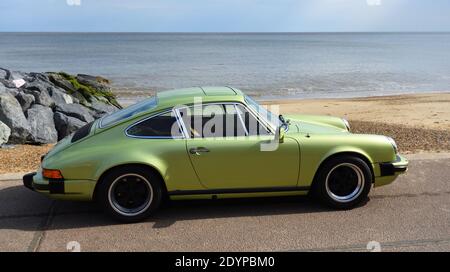 Auto a motore Classic Green Porsche parcheggiata sul lungomare in background. Foto Stock