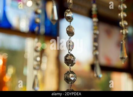 Cordoncino con cristalli di lampadario che catturano la luce. Sullo sfondo altri cordoni di cristallo, fiasche di vetro e altri oggetti. Feng Shui Foto Stock