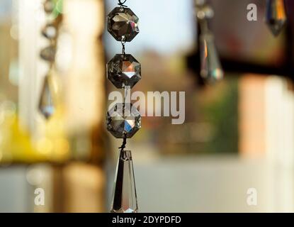 Cristalli di lampadario che catturano la luce. Sullo sfondo un bokeh colorato di oggetti diversi nella finestra. Feng Shui Foto Stock