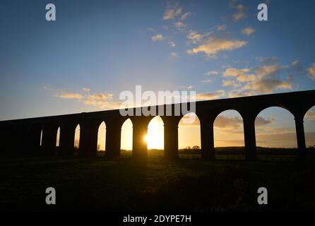 Il sole tramonta dietro il Viadotto di Harringworth, conosciuto anche come Welland Valley Viadotto sul confine del Rutland e Northamptonshire Foto Stock