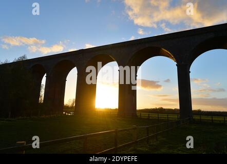 Il sole tramonta dietro il Viadotto di Harringworth, conosciuto anche come Welland Valley Viadotto sul confine del Rutland e Northamptonshire Foto Stock