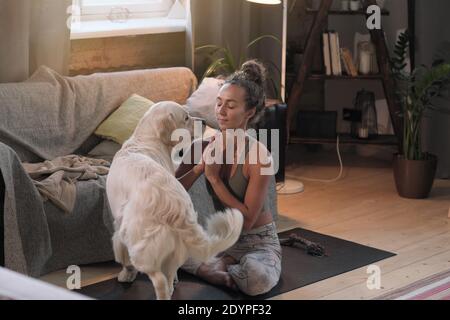 Giovane donna meditando in lotus posizione nella stanza insieme con il suo cane Foto Stock