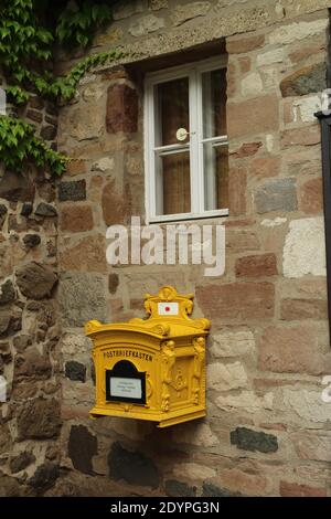 Vecchia e antica letterbox gialla appesa al muro di una vecchia casa tedesca. Foto Stock