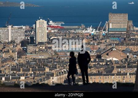 La silhouette di una coppia che si trova sulla collina di Calton guardando verso nord verso Leith e il Firth of Forth a Edimburgo, Scozia, Regno Unito. Foto Stock