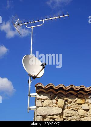 Rastrello antenna e parabolica su un vecchio tetto. Foto Stock