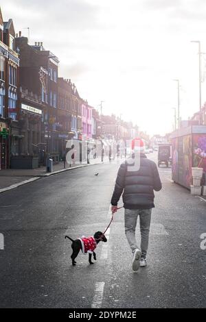 Camminando il cane che indossa un vestito di Babbo Natale in un High Street a Londra il giorno di Natale 2020 Foto Stock