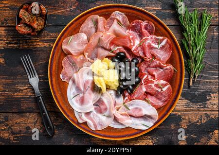 Piatto di carne italiana con prosciutto, bresaola, pancetta, salame e parmigiano. Sfondo di legno scuro. Vista dall'alto Foto Stock