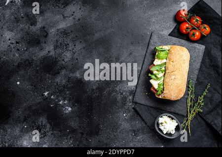 Panino di ciabatta con formaggio Camembert fresco, marmellata di pere e rucola. Sfondo nero. Vista dall'alto. Spazio per il testo Foto Stock