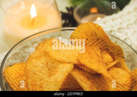 Fiches di papato scanalati in ciotola trasparente su sfondo accogliente, maglione, decorazione invernale, composizione con spazio per la copia Foto Stock