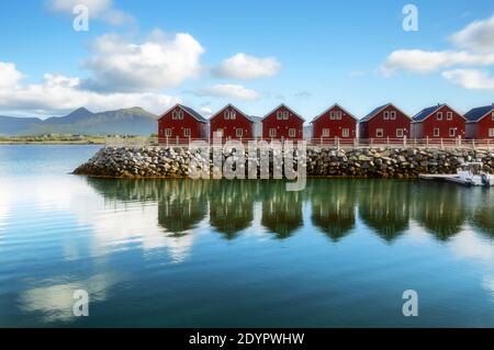 Tradizionali case di legno rosso sulla riva del fiordo di Offersoystraumen. Fantastico tramonto estivo sull'isola di Vestvagoy. Pittoresca vista serale di Lofoten Foto Stock