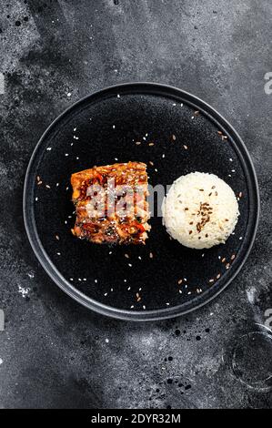 Filetto di salmone alla griglia di Teriyaki giapponese smaltato in deliziosa salsa con un contorno di riso. Sfondo nero. Vista dall'alto Foto Stock