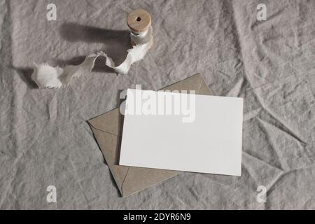 Matrimonio Moody ancora vita, composizione tabella. Biglietto d'auguri vuoto, scena di invito mockup con busta artigianale e nastro di seta. Tovaglie di lino con retro Foto Stock