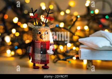 Le luci di Natale bokeh con una decorazione fatta a mano cervi fatto di tappo di champagne che tiene una candela avendo un curioso e sorpreso Foto Stock