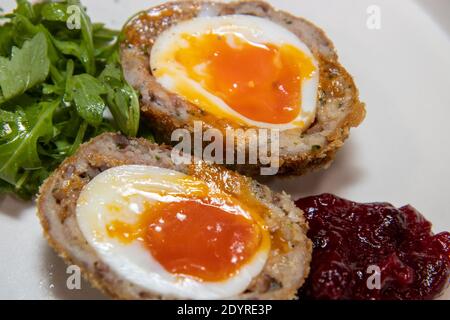 Un delizioso uovo di scotch fatto in casa su un piatto bianco con insalata Foto Stock