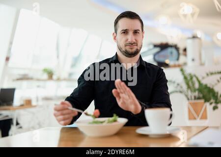 Non voglio mangiare questo giovane con la barba è sconvolto con il piatto che il cameriere lo ha servito. L'uomo è deluso dal suo ristorante preferito. Cibo cattivo e. Foto Stock