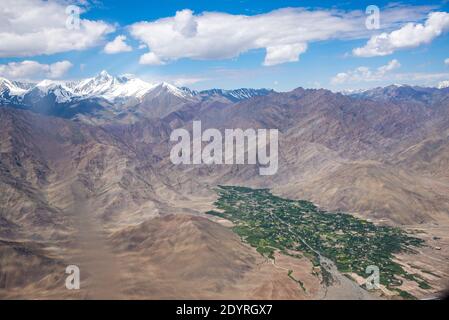 Vista sulla catena montuosa con villaggio nella valle verde a Ladakh, India Foto Stock