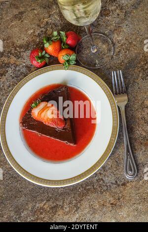 Terrina di cioccolato fatta in casa con una salsa di fragole fresca guarnita con una fragola fresca tagliata a fette Foto Stock