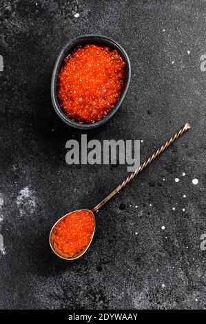 Salmone caviale rosso in un cucchiaio squisito. Sfondo nero. Vista dall'alto Foto Stock