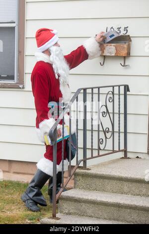 Winneconne, WI-23 dicembre 2020: Un vettore di lettera del lavoratore postale USPS è vestito in su come Babbo Natale mentre consegna la posta ad una casa. Foto Stock