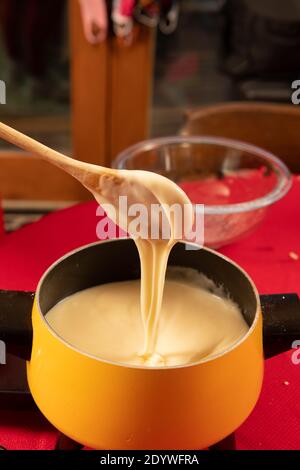 Il formaggio svizzero viene mescolato e testato per la cena di fonduta Foto Stock