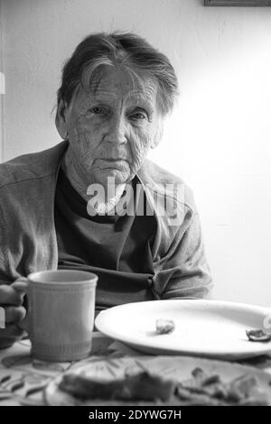 Una donna di 84 anni che soffre di depressione, con una tazza di caffè. Foto Stock