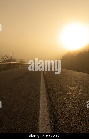 Bella immagine di una strada in una giornata di nebbia durante il sorgere del sole. Primo piano guardando il asfalto. Scatto basso Foto Stock