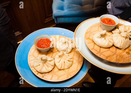 Succulento khinkali su un piatto bianco. Servito con salsa. Piatto tradizionale. Foto Stock