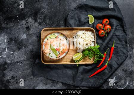 Tom Kha Gai. Zuppa di cocco cremosa e speziata con pollo e gamberi. Cibo tailandese. Sfondo nero. Vista dall'alto Foto Stock