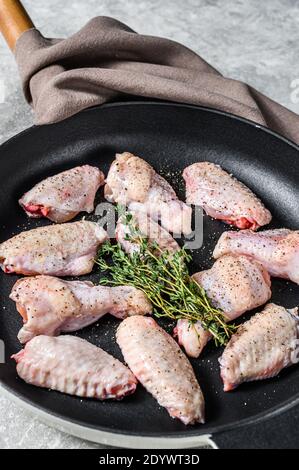 Ali di pollo marinate con spezie ed erbe in una padella. Sfondo grigio. Vista dall'alto Foto Stock