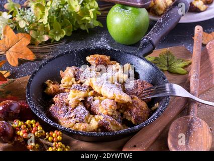 il delizioso kaiserschmarrn austriaco fatto in casa in una rustica padella di ferro tavolo di legno Foto Stock