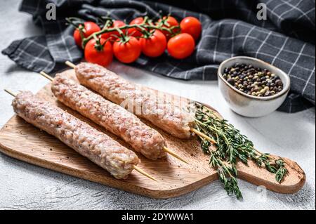 Spiedini freschi crudi di carne di maiale tritata kebab. Sfondo bianco. Vista dall'alto Foto Stock