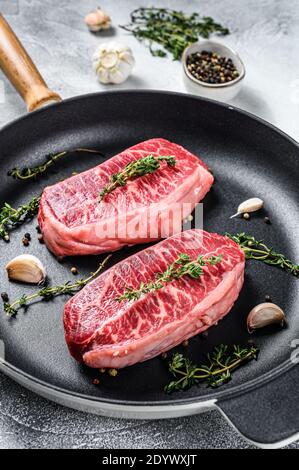 Bistecca grezza in padella. Sfondo grigio. Vista dall'alto Foto Stock