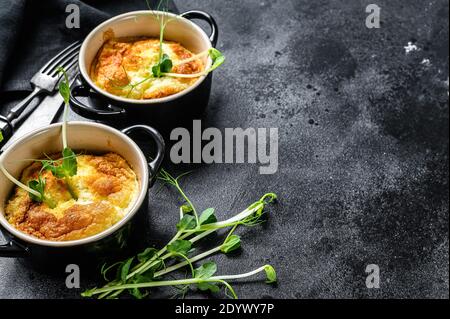 Omelette di formaggio , omelette con micrograni in una padella. Sfondo nero. Vista dall'alto. Spazio di copia Foto Stock