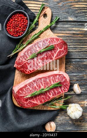 Bistecca di manzo crudo marmorizzato, bistecca di carne con lama superiore. Sfondo nero. Vista dall'alto Foto Stock