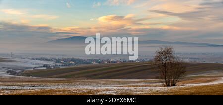 Bellissimo paesaggio della Slovacchia - campi ondulati, montagne, soffiato dalla neve, avvolto nella nebbia mattutina Foto Stock