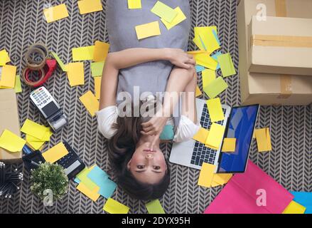 Freelancer esausto che prende un pisolino nel sonno sul pavimento all'ufficio domestico. Donna attraente a casa Foto Stock